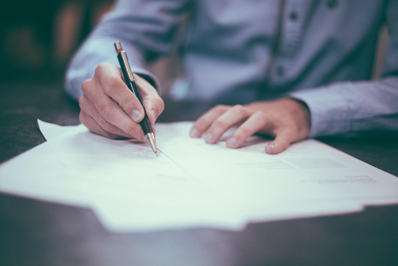 Someone signing documents with a pen